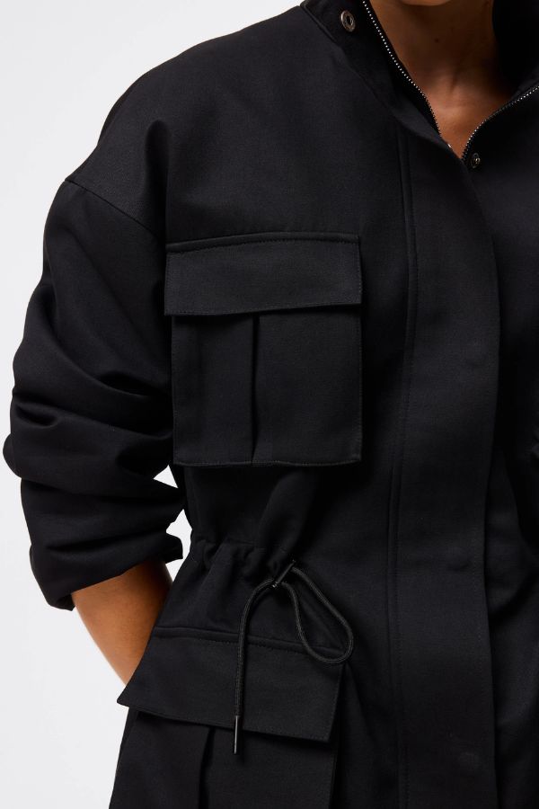Mossman My Muse Anorak in Black, a modern utility jacket featuring oversized flap pockets, adjustable drawstring waist, and a concealed zip front for an elevated off-duty look. 4 