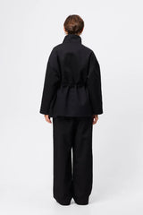 Mossman My Muse Anorak in Black, a modern utility jacket featuring oversized flap pockets, adjustable drawstring waist, and a concealed zip front for an elevated off-duty look.