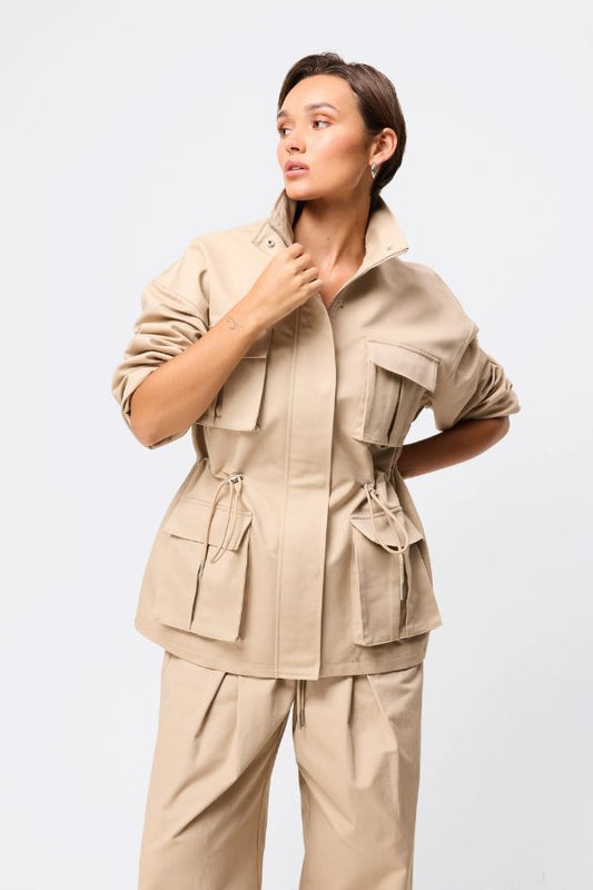 Mossman My Muse Anorak in Natural, a timeless utility jacket with oversized flap pockets, adjustable drawstring waist, and a concealed zip front for effortless layering.