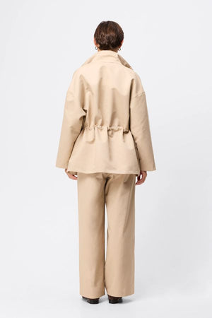 Mossman My Muse Anorak in Natural, a timeless utility jacket with oversized flap pockets, adjustable drawstring waist, and a concealed zip front for effortless layering.