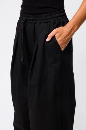 Mossman Tied Down Pant in Black, a wide-leg cotton pant featuring an elasticated waistband with adjustable toggle and functional pockets for chic utility style.