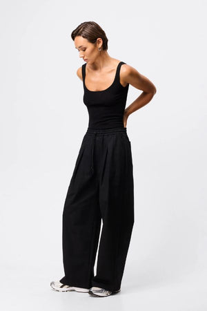 Mossman Tied Down Pant in Black, a wide-leg cotton pant featuring an elasticated waistband with adjustable toggle and functional pockets for chic utility style.