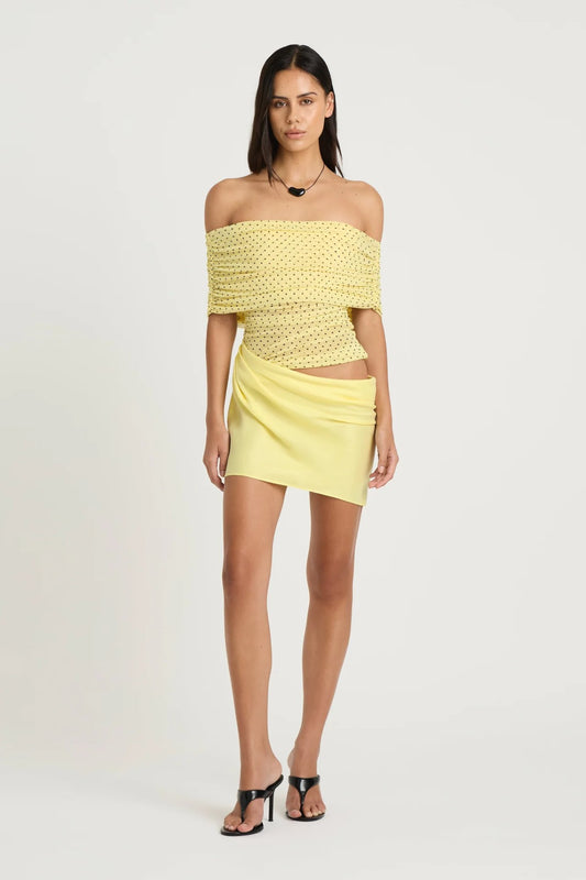 Nico Off Shoulder Mini Dress Yellow Spot by Benni, a sheer mesh mini with draped cupro skirt and cowl waist. Perfect for statement dressing.