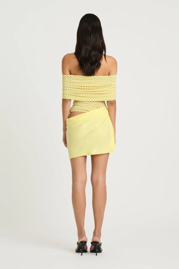 Nico Off Shoulder Mini Dress Yellow Spot by Benni, a sheer mesh mini with draped cupro skirt and cowl waist. Perfect for statement dressing.