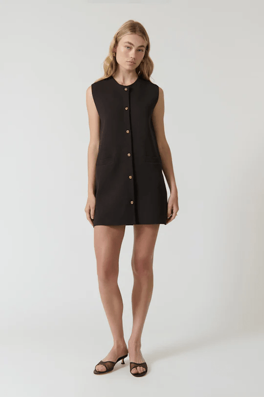 Nanda Dress Chocolate by Onte – Playful sleeveless mini shift with gold knot buttons, crew neck, welt pockets, and a flattering straight fit. Perfect for chic daytime events and casual outings.