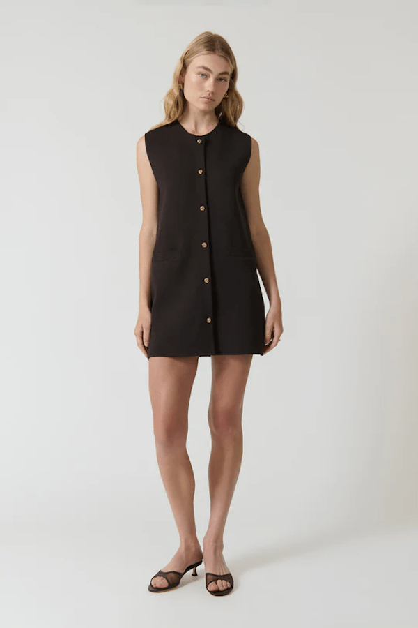 Nanda Dress Chocolate by Onte – Playful sleeveless mini shift with gold knot buttons, crew neck, welt pockets, and a flattering straight fit. Perfect for chic daytime events and casual outings.