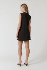 Nanda Dress Chocolate by Onte – Playful sleeveless mini shift with gold knot buttons, crew neck, welt pockets, and a flattering straight fit. Perfect for chic daytime events and casual outings.