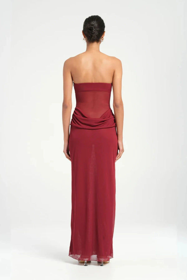 Petra Maxi Dress Wine by Benni, a strapless bandeau dress with a panelled waist, sheer mesh torso, and signature cowl drape for modern elegance. Perfect for formal events