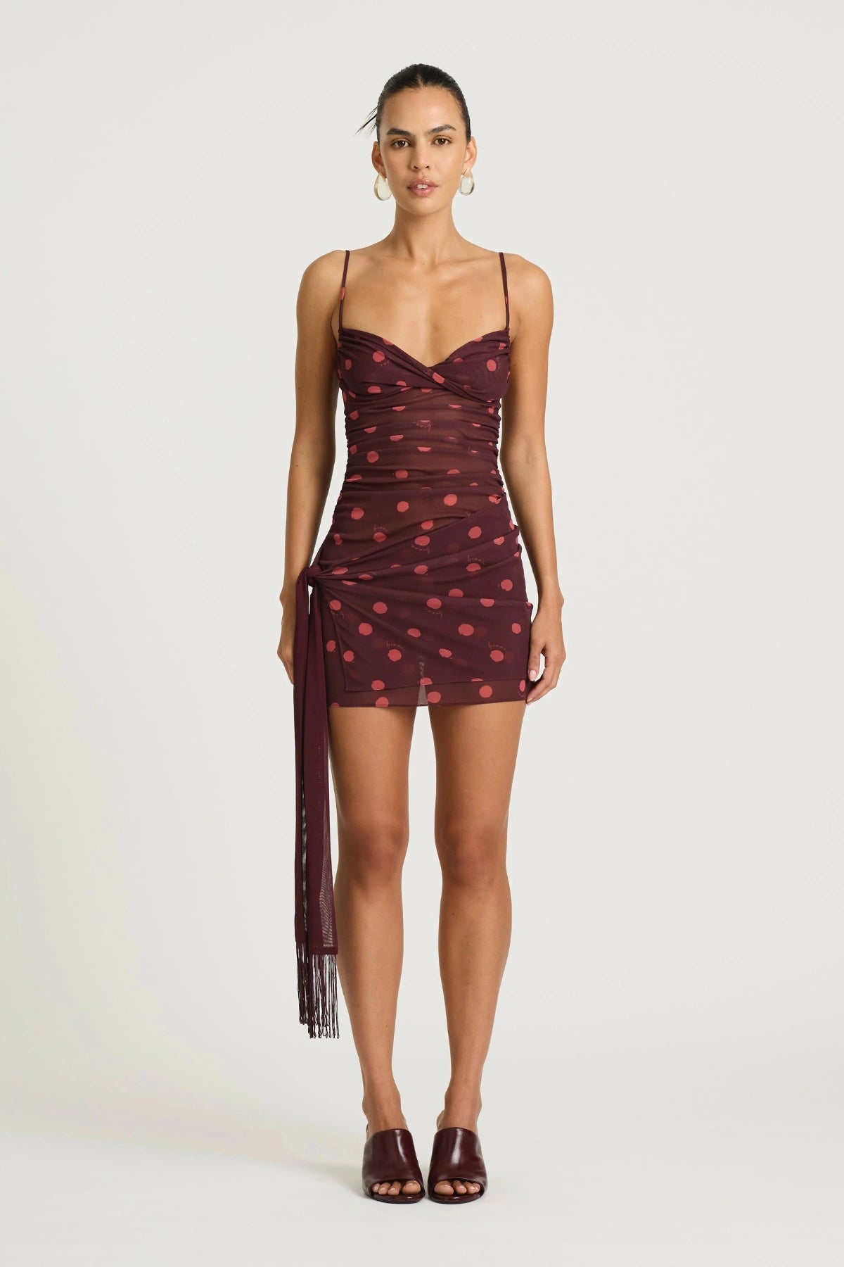 Piper Twist Dress Plum Spot by Benni, a twisted cami mini with draped overlay and tassel waist tie for elevated day-to-night dressing.
