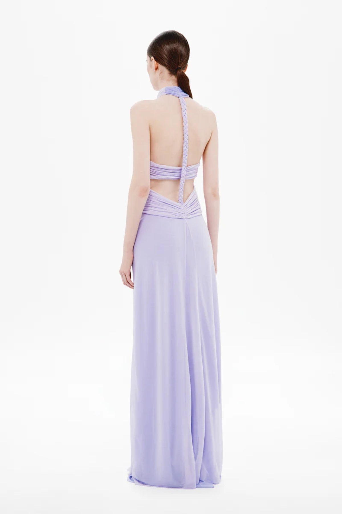 Pippa Braid Dress by Misha, a halter maxi in fluid jersey with crossover bodice, sheer midsection, and sculptural braided back for timeless elegance.