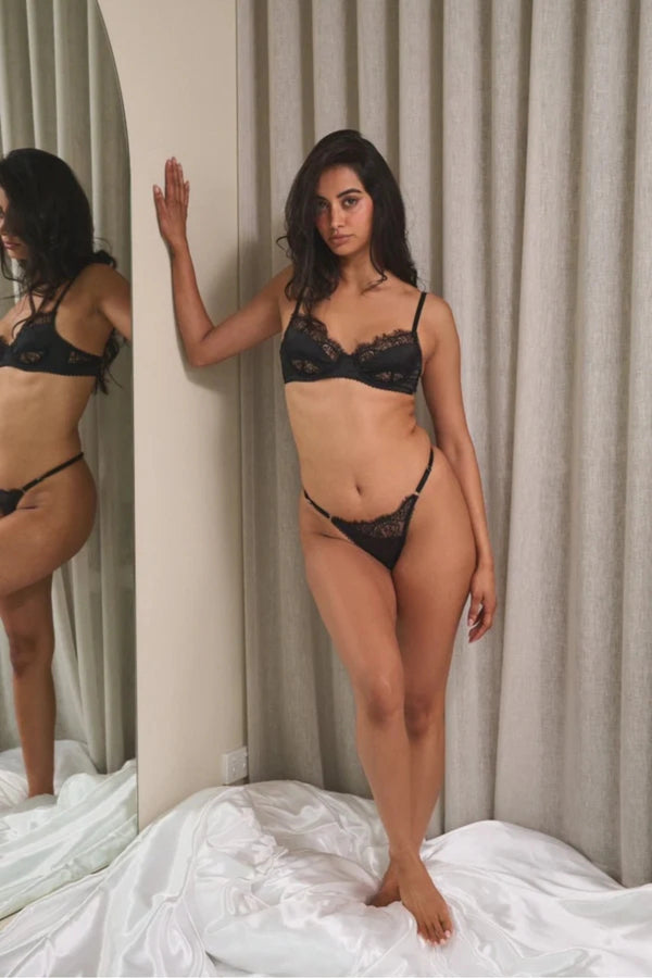 Kat the Label Rae Thong Black, vintage-inspired satin with asymmetrical lace, eyelash trim, mesh back, and adjustable sides for a perfect fit.