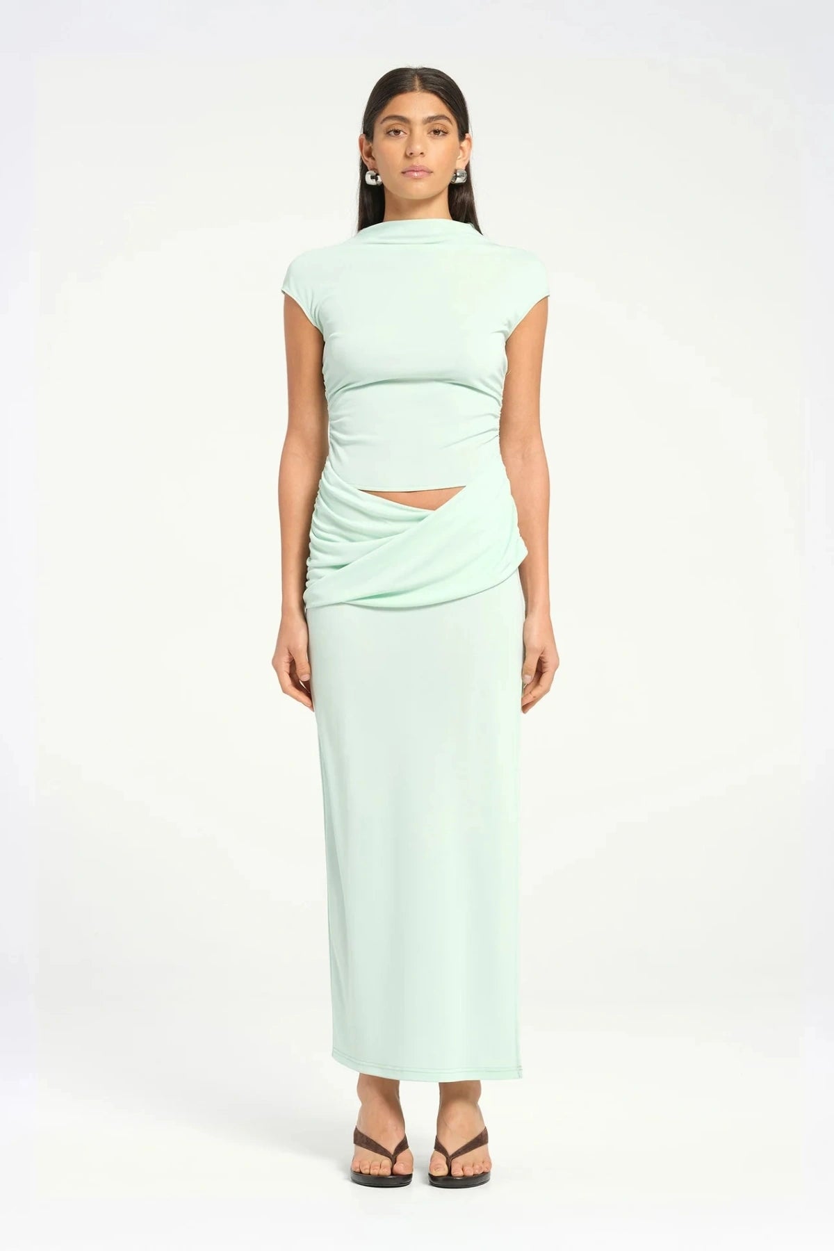 Royce Maxi Dress Aqua by Bec + Bridge, a sleek silhouette with a twisted waist, cowl detail, and side split, perfect for modern evening dressing.