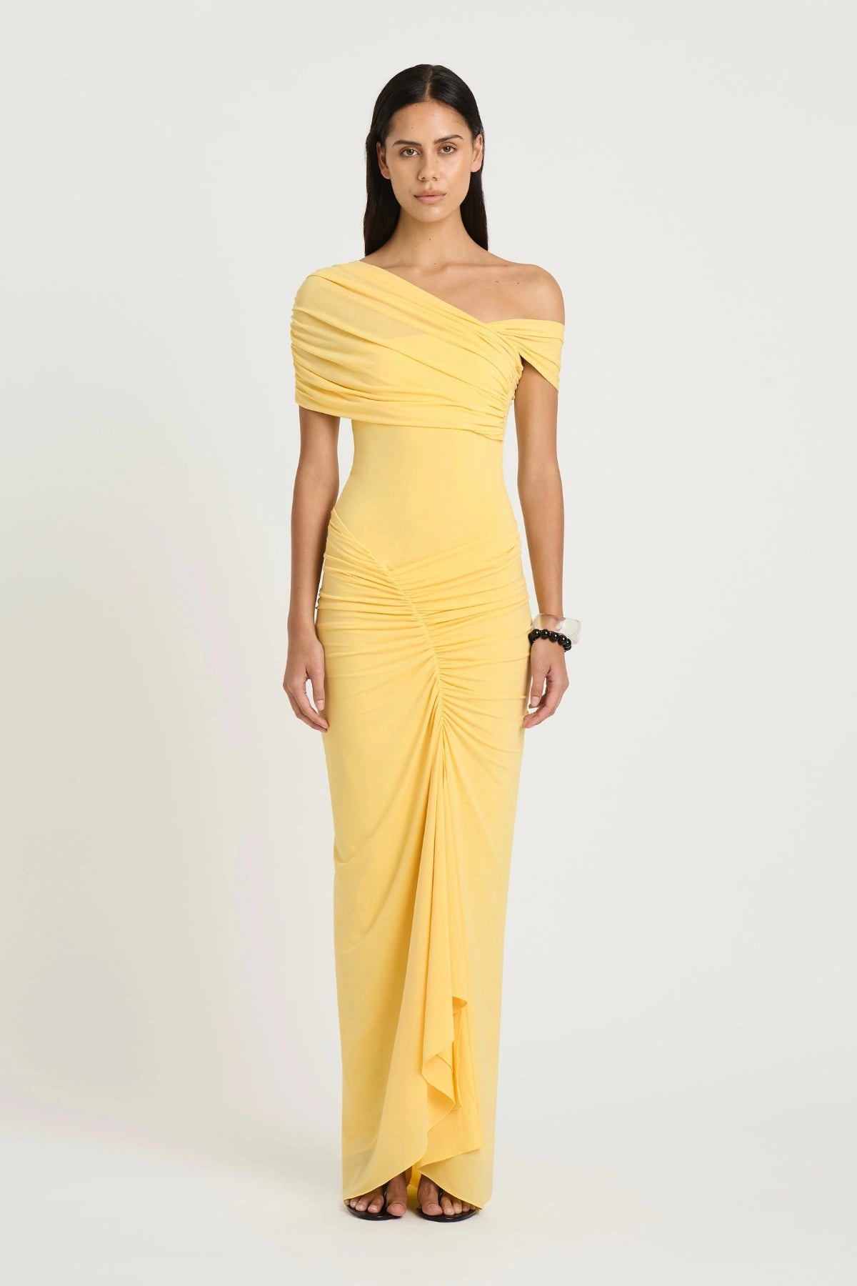 Rumi Maxi Dress by Benni — an asymmetric stretch jersey dress with a gathered skirt and cascading split, offering sheer or solid styling options.
