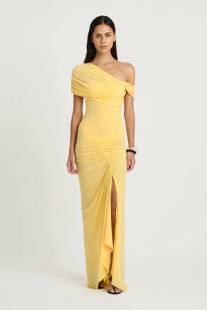Rumi Maxi Dress by Benni — an asymmetric stretch jersey dress with a gathered skirt and cascading split, offering sheer or solid styling options.
