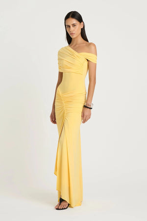 Rumi Maxi Dress by Benni — an asymmetric stretch jersey dress with a gathered skirt and cascading split, offering sheer or solid styling options.
