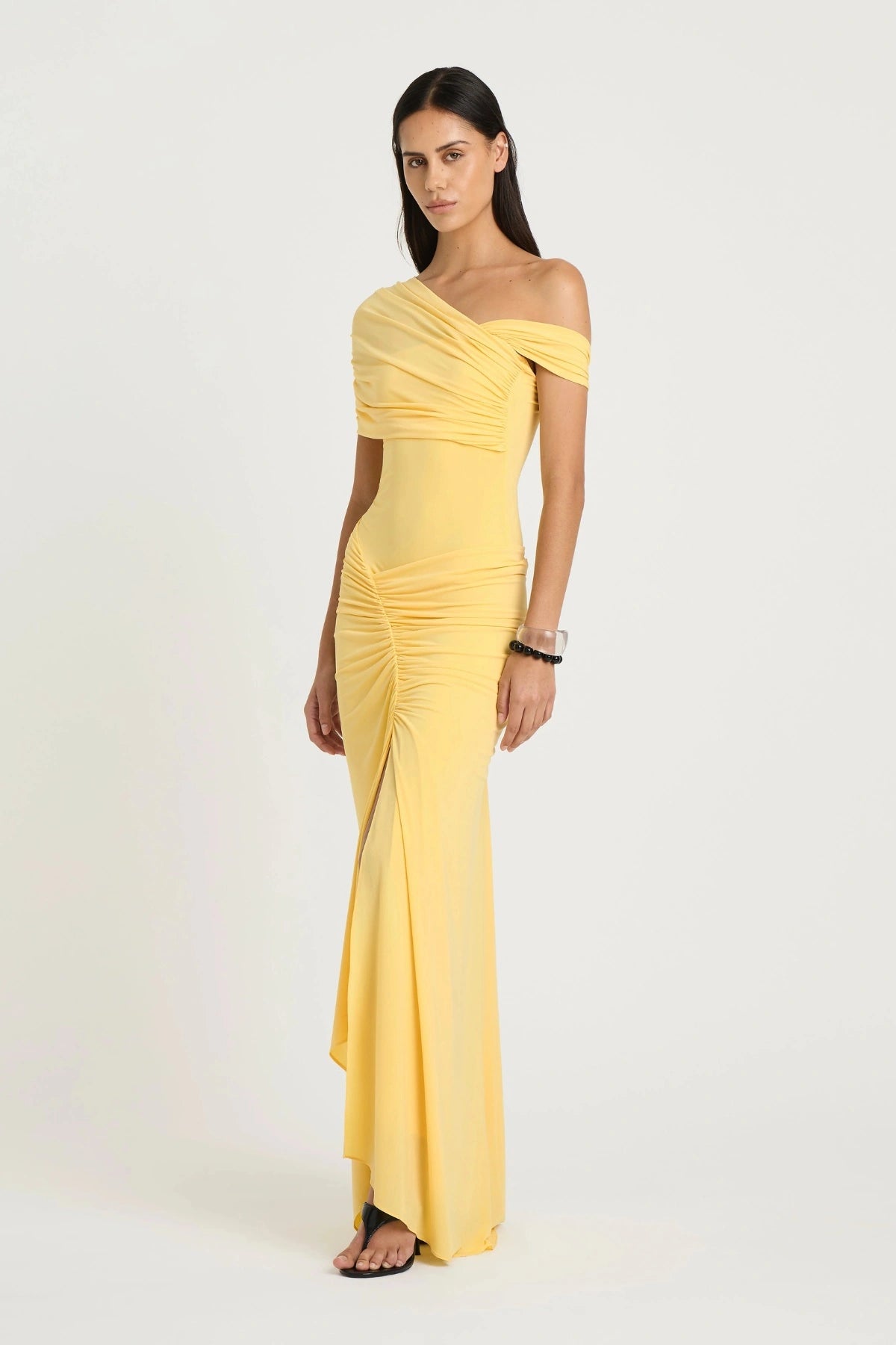 Rumi Maxi Dress by Benni — an asymmetric stretch jersey dress with a gathered skirt and cascading split, offering sheer or solid styling options.
