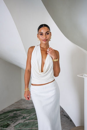 Saint Plunge Top Ivory by Sneaky Link – A sultry halter-neck tie top with a daring plunge neckline and low back. Crafted from a silky blend of 90% cupro and 10% spandex for a sleek, stretchy fit. Perfect for nights out or special occasions.