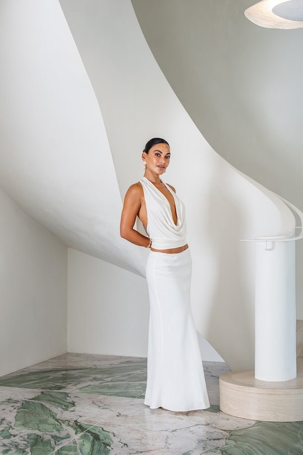 Saint Plunge Top Ivory by Sneaky Link – A sultry halter-neck tie top with a daring plunge neckline and low back. Crafted from a silky blend of 90% cupro and 10% spandex for a sleek, stretchy fit. Perfect for nights out or special occasions.