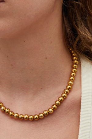 Sol Necklace Gold by Heaven Mayhem – polished gold bead necklace with signature S-clasp for layering.