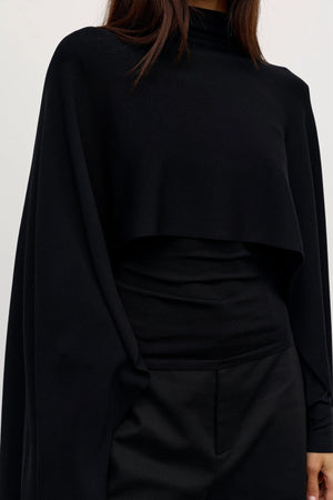 Sorella Poncho Black by Bayse – a draped knit poncho with mock neckline and relaxed fit. Perfect for layered styling.