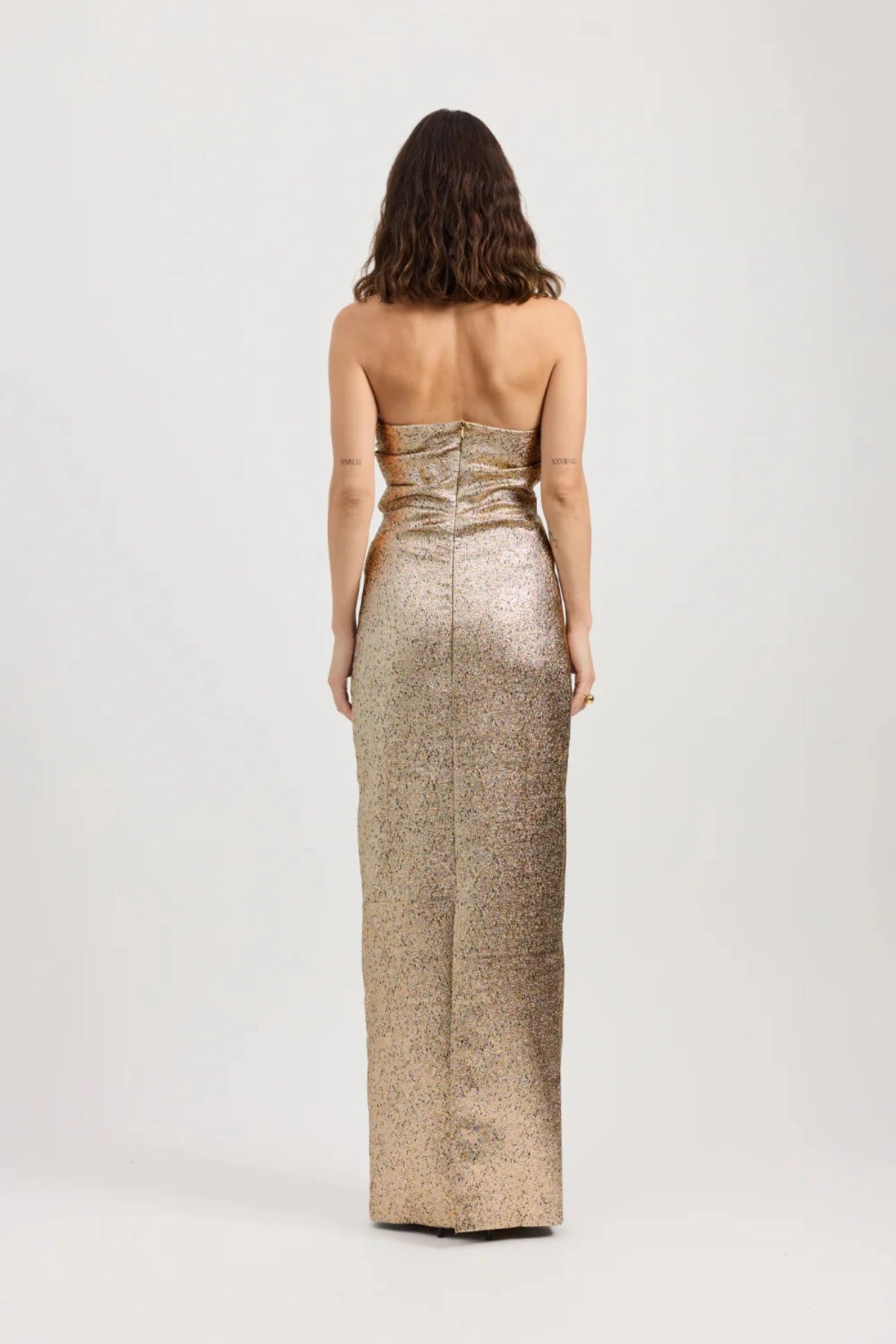 Tacoma Dress by Tojhà, a metallic champagne strapless gown with fold-over neckline, side tucks, and back split for sculptural elegance.