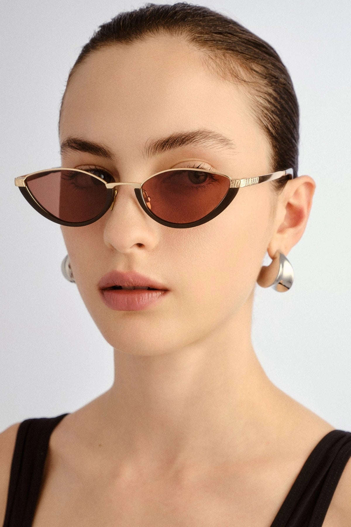 The Lia sunglasses by Luv Lou, black cat-eye frame with metal accents and debossed Organic L pattern, featuring smoke mono lenses.