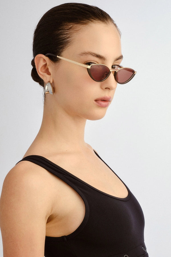 The Lia sunglasses by Luv Lou, black cat-eye frame with metal accents and debossed Organic L pattern, featuring smoke mono lenses.