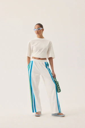 Vacation Sporty Pant by Araminta James — a white wide-leg sports-sheen pant with velour trims and elastic waist, perfect for relaxed styling.