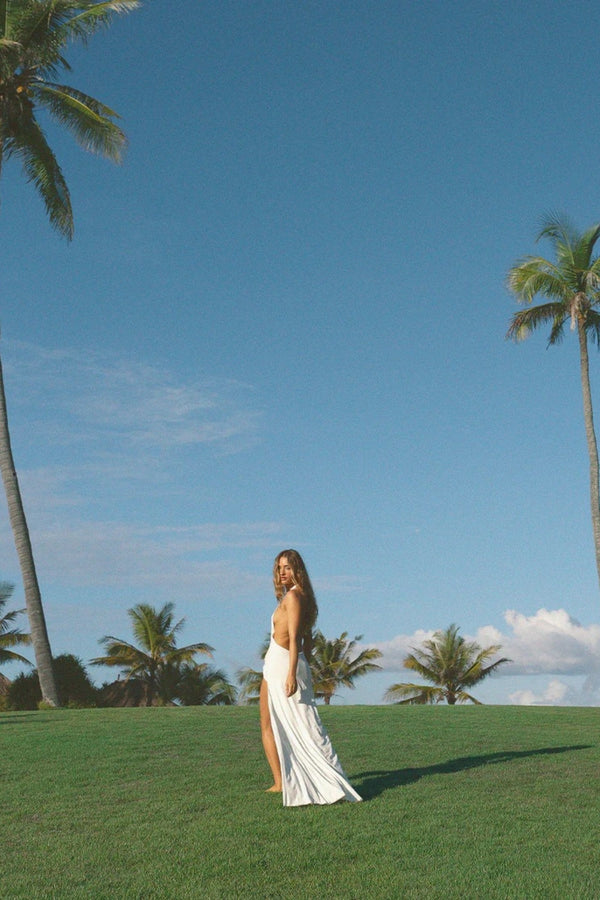 Winona Gown White by Natalie Rolt – a draped halter gown with open back and side split. Perfect for formal evening events.