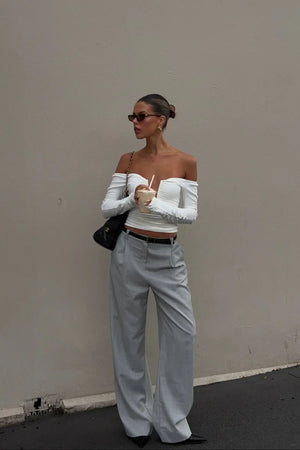 White off-shoulder top with ruffled neckline and short sleeves, styled on a mannequin.