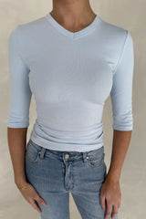 Person wearing an Esme High V light blue ribbed top with 3/4 sleeves paired with blue denim jeans against a neutral background.