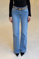 Woman wearing Kendall Mid Rise Flare Jean in mid wash paired with a black top, snake-print belt, and black pointed-toe shoes.