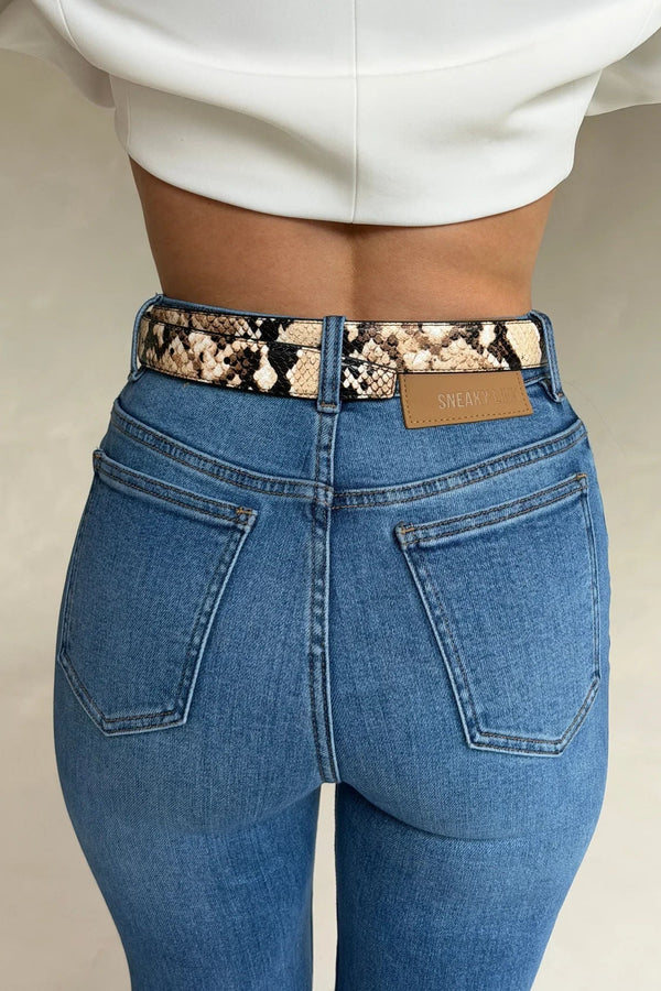 Rear view of Kennedy Crop Jean Indigo showing high-waisted blue denim with a snakeskin belt and tan SNEAKY LINK patch.