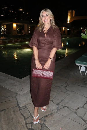 Woman in a brown dress standing by a pool at night