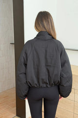 Person wearing a black Maddison Shawl Collar Oversized Jacket with cropped elastic hem and matching black leggings, seen from behind.