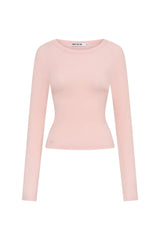 The Polly Long Sleeve top in pink. Woman in a pink top and white pants standing outside a store with plants and a bench in the background.