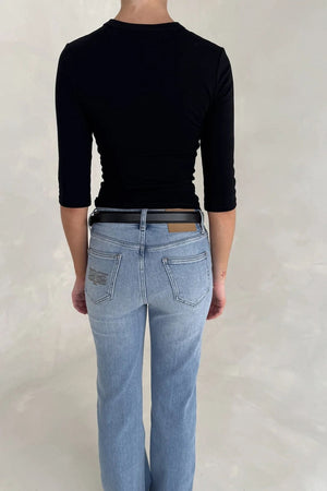 Rear view of a woman wearing light-wash jeans with a Renee Leather Belt Black and a black three-quarter sleeve top.