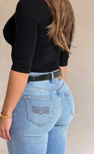 Woman wearing light-wash Celine high-rise jeans with embroidered logo, black long-sleeve top, and Renee Leather Belt Black Croc.