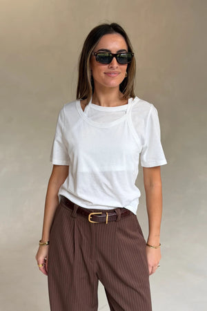 Woman wearing a Renee Leather Belt Chocolate with brown pinstriped trousers, white layered tee, gold jewelry, and black sunglasses.
