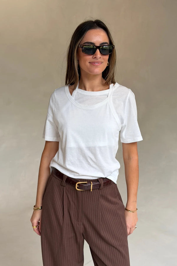 Woman wearing a Renee Leather Belt Chocolate with brown pinstriped trousers, white layered tee, gold jewelry, and black sunglasses.