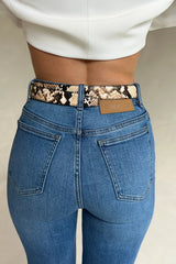 Close-up rear view of high-waisted blue jeans with a Renee Leather Belt Snake featuring a snakeskin pattern and a tan SNEAKY LINK patch.