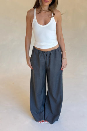 Woman wearing tailored wide-leg grey Zoe Relaxed Suit Pants paired with a white halter tank and white square-toe sandals.
