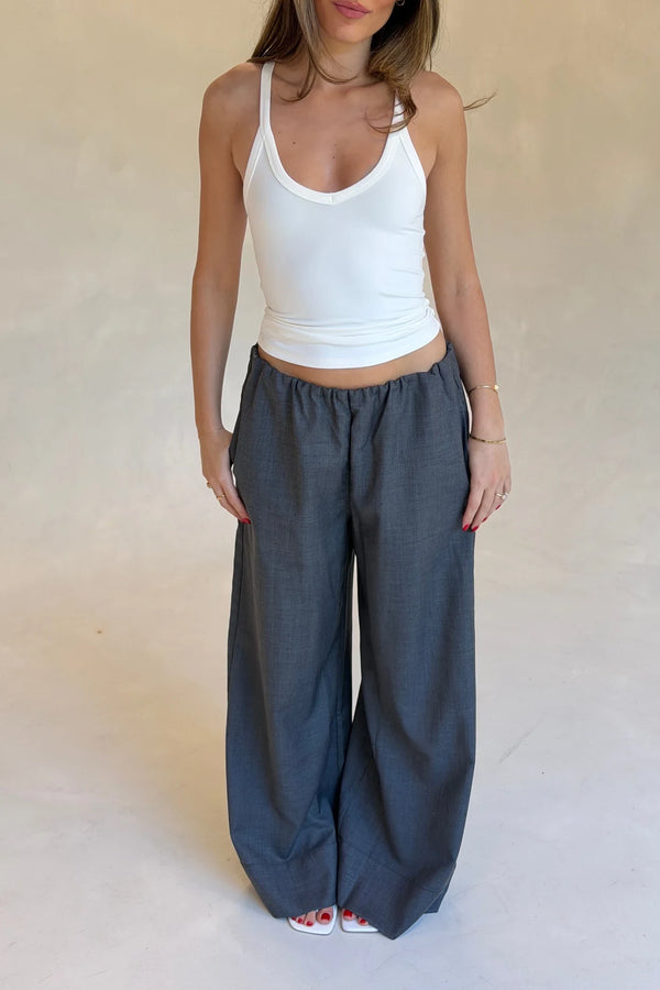Woman wearing tailored wide-leg grey Zoe Relaxed Suit Pants paired with a white halter tank and white square-toe sandals.