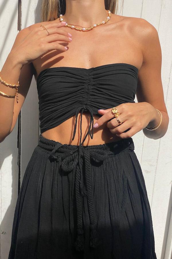 Ruched Tube Top Black by D’Artemide, Cotton bandeau with ruched back and front tie detail for easy summer layering or elevated resort styling.